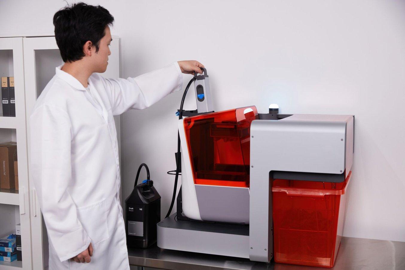 Person im Laborkittel setzt eine Resin Pump in den 3D-Drucker Form 3B+ ein