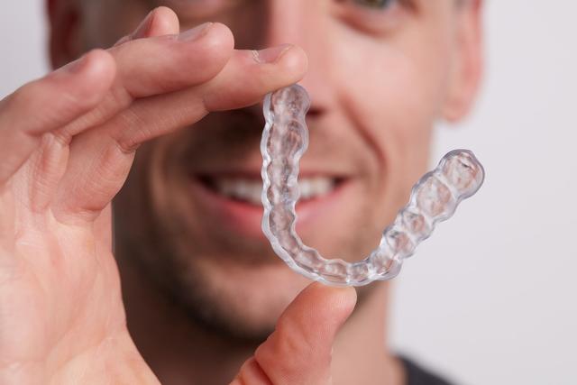 Clear occlusal spine being held up in front of a man's face