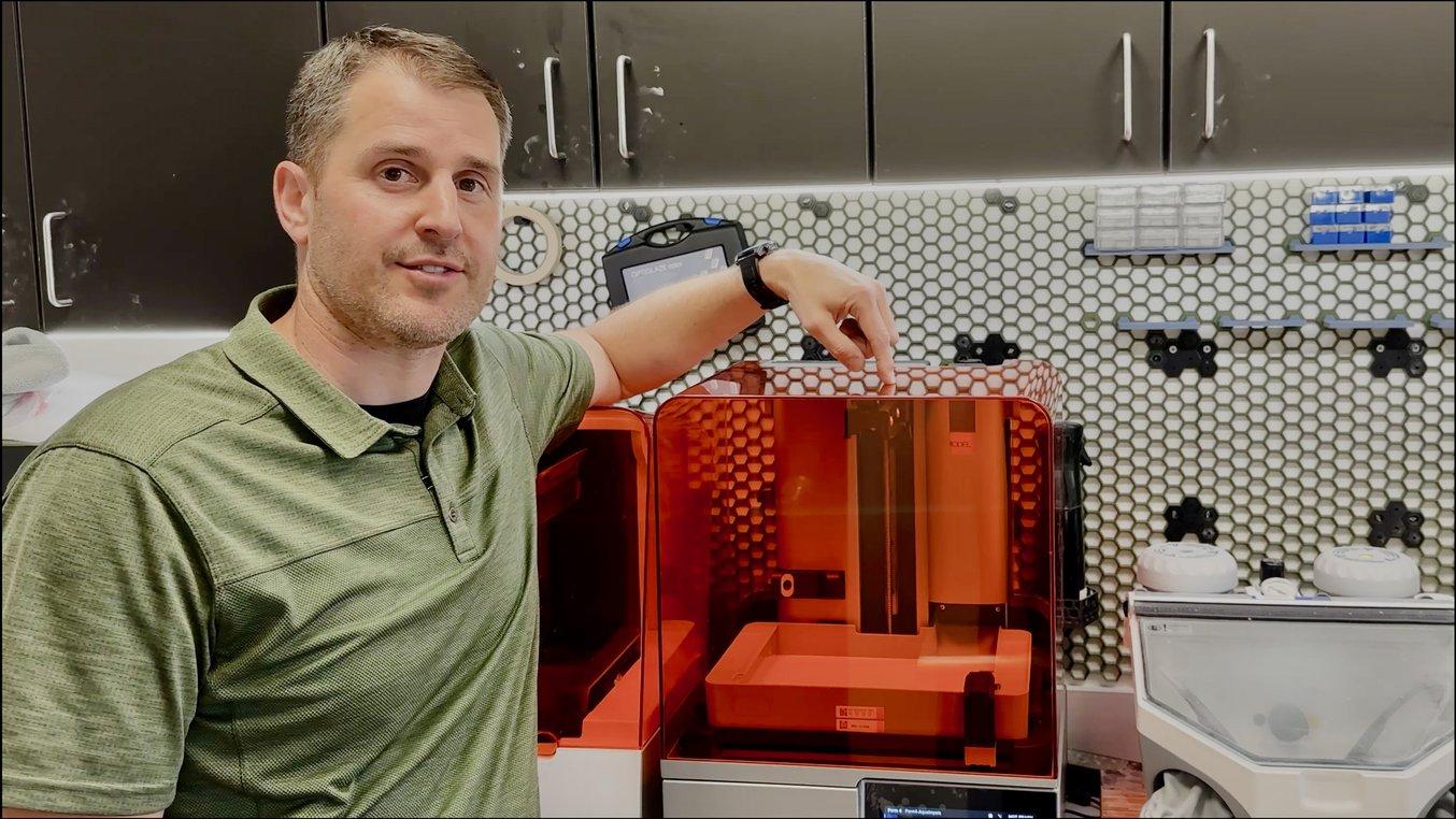 Dr. Baer zeigt auf den 3D-Drucker Form 4B in einer Zahnarztpraxis