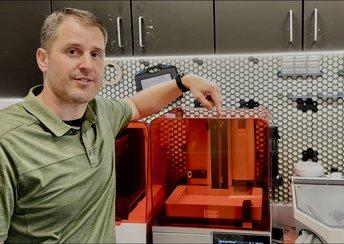 Dr. Baer pointing to the Form 4B 3D printer in a dental office