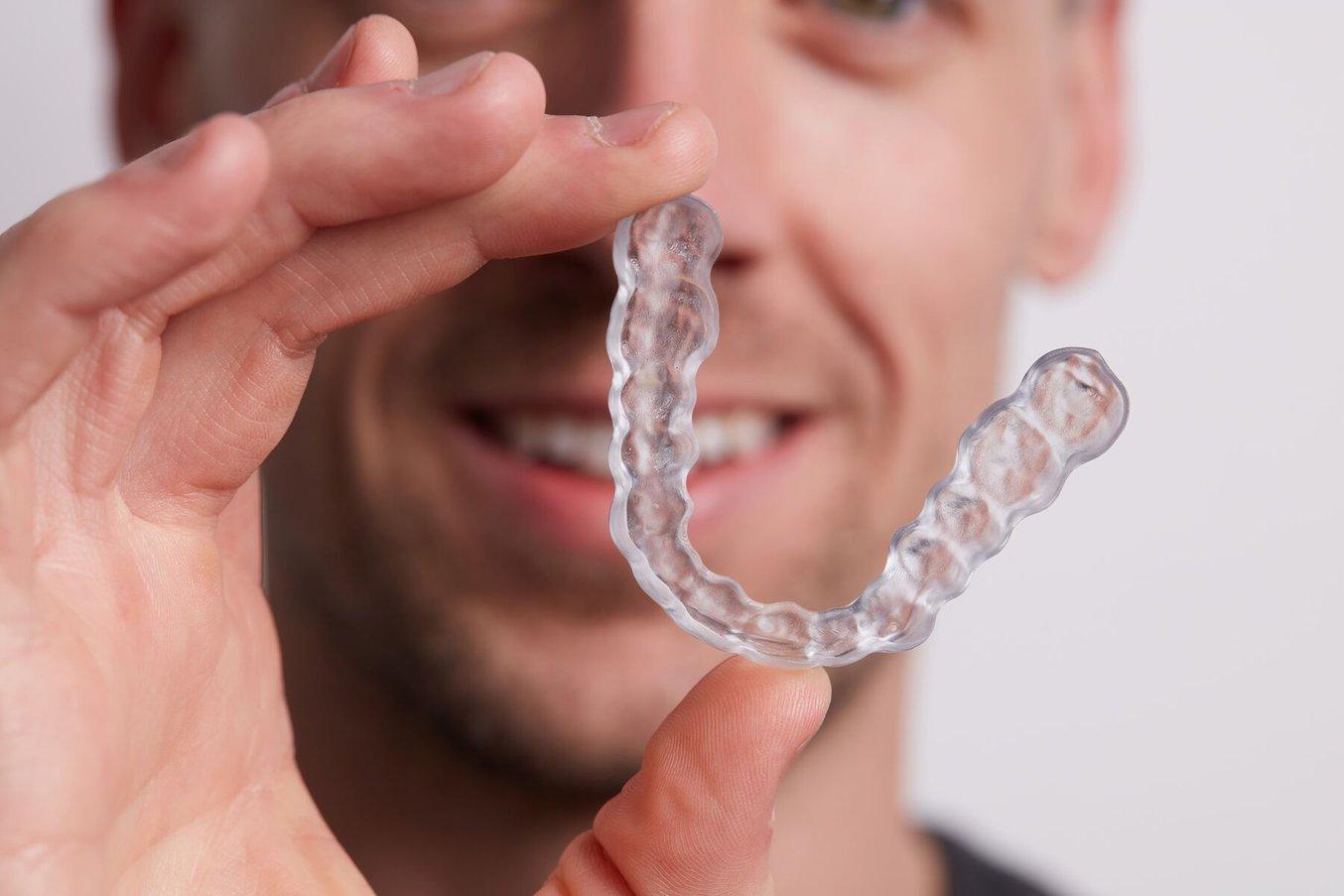 Man holding up a clear occlusal splint in front of his face