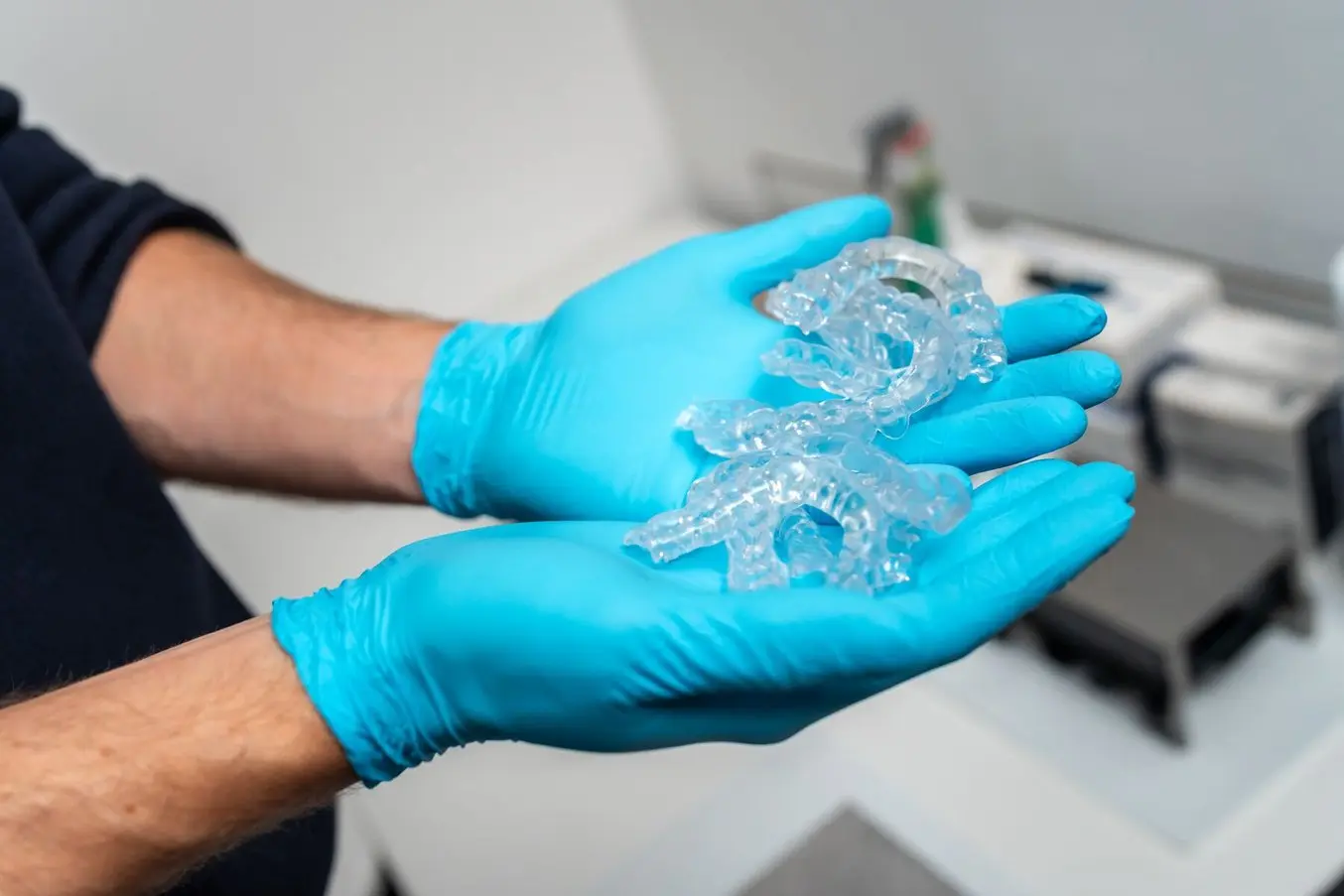 Person wearing gloves holding occlusal splints