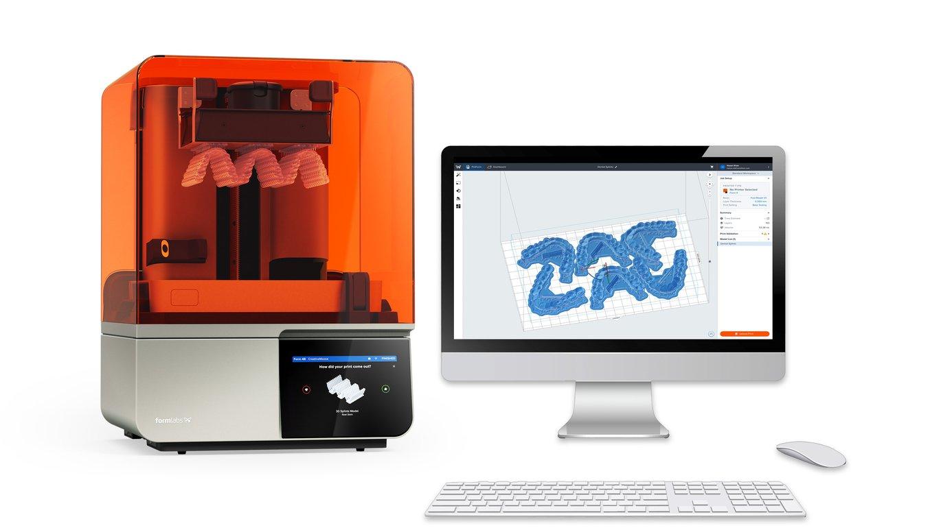 The Formlabs Form 4 3D printer next to a desktop monitor showing PreForm