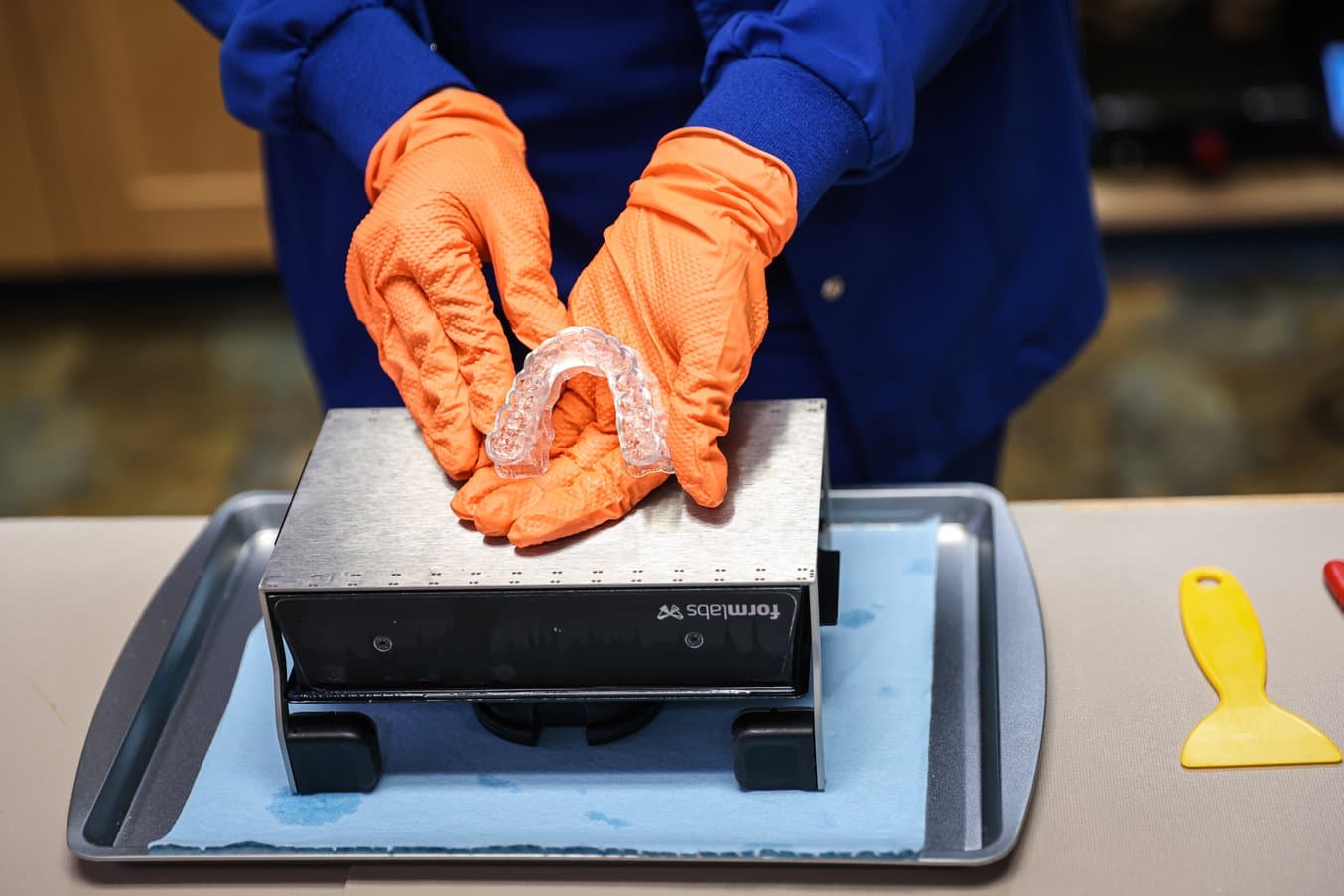 Gloved hands holding occlusal splint above a Build Platform Flex