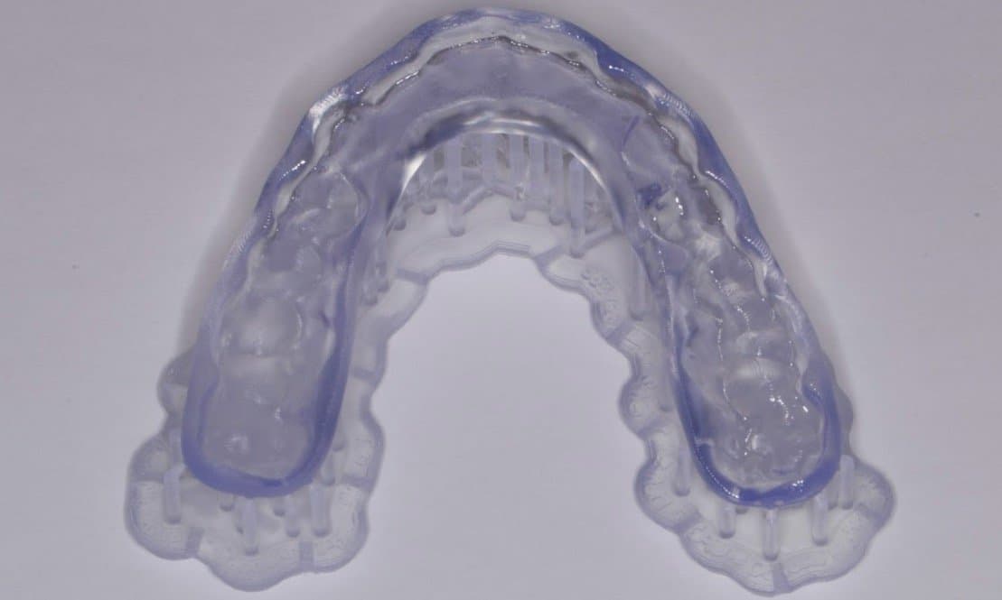 Printed occlusal splint still on support structures and after curing.