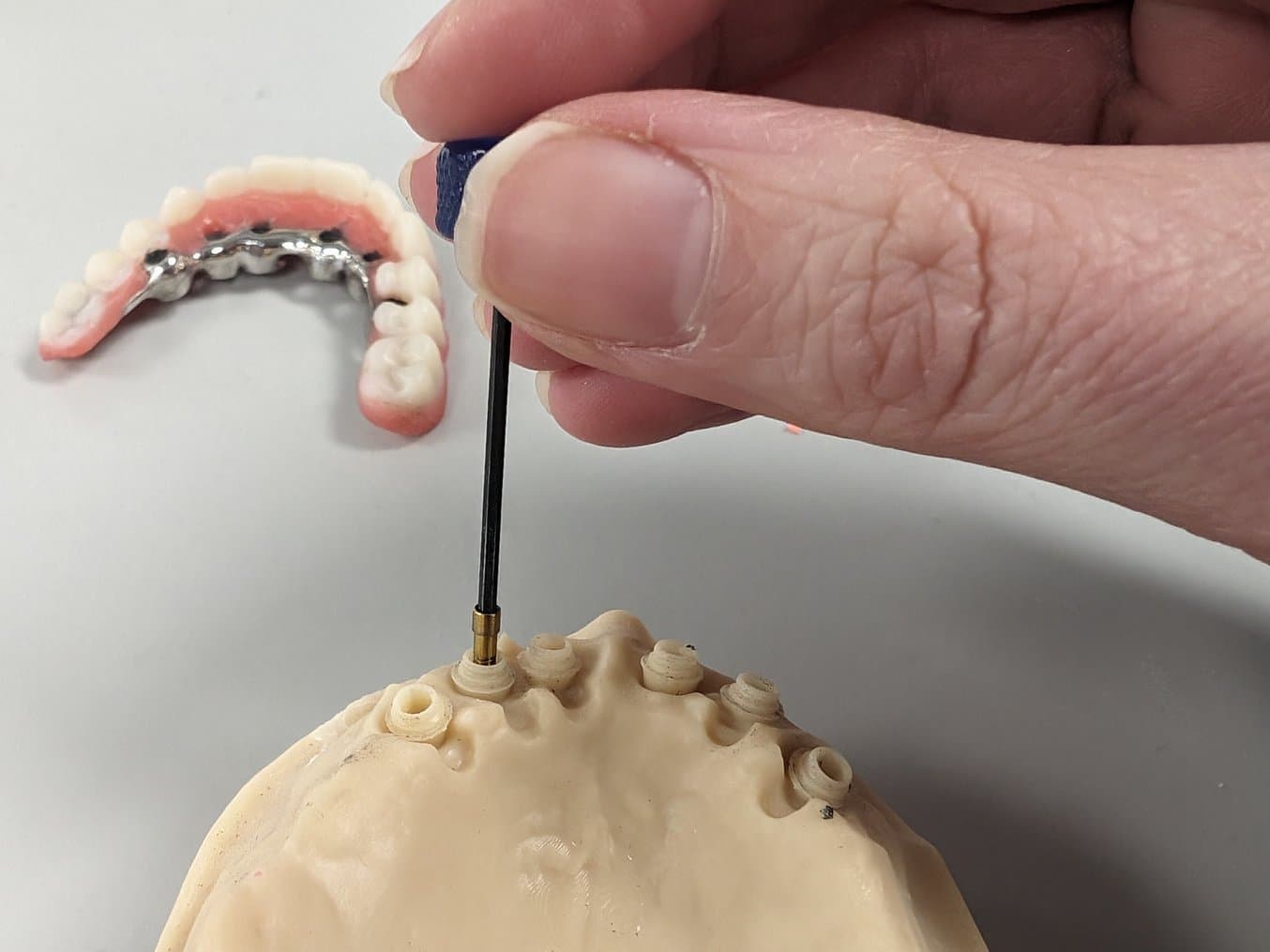 Person screwing a part into a restorative model
