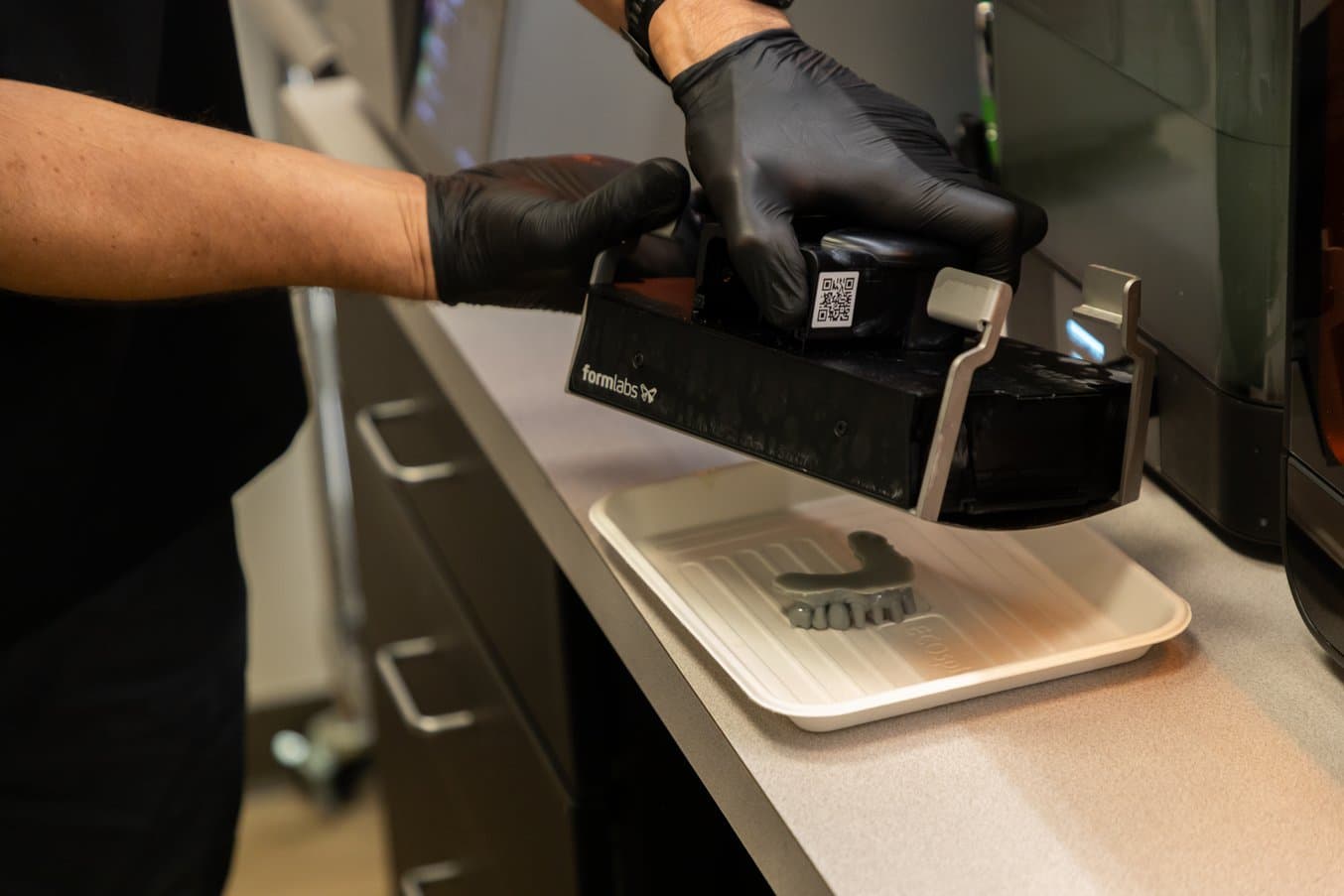 Gloved hands flexing the handles on Flex Build Platform to remove a 3D printed model