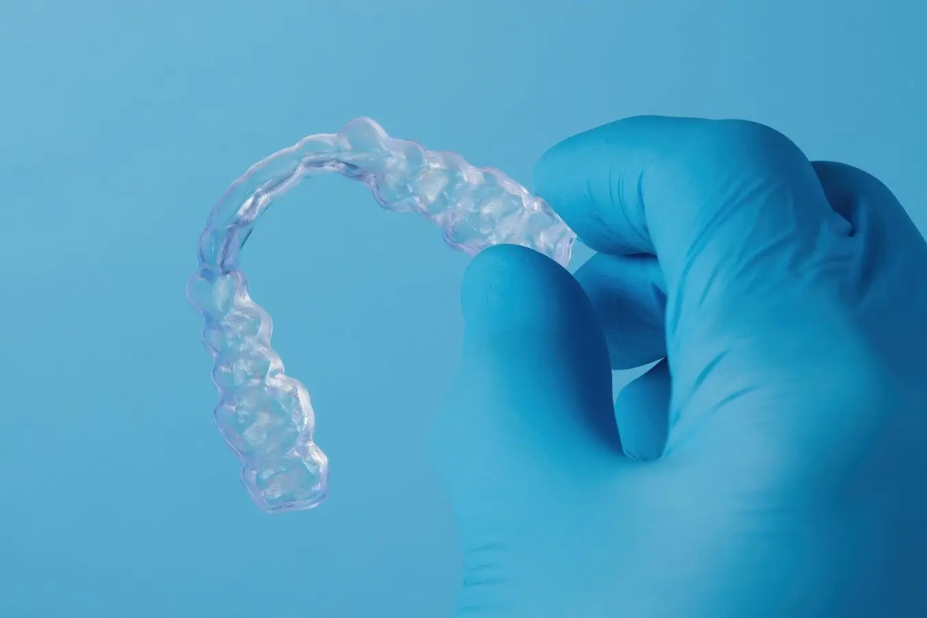 Hand holding a dental model 3D printed using the new Dental LT Clear V2 Resin on a blue background