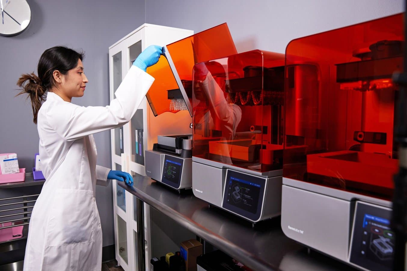 Dental technician lifting the hood of a Form 4B 3D printer