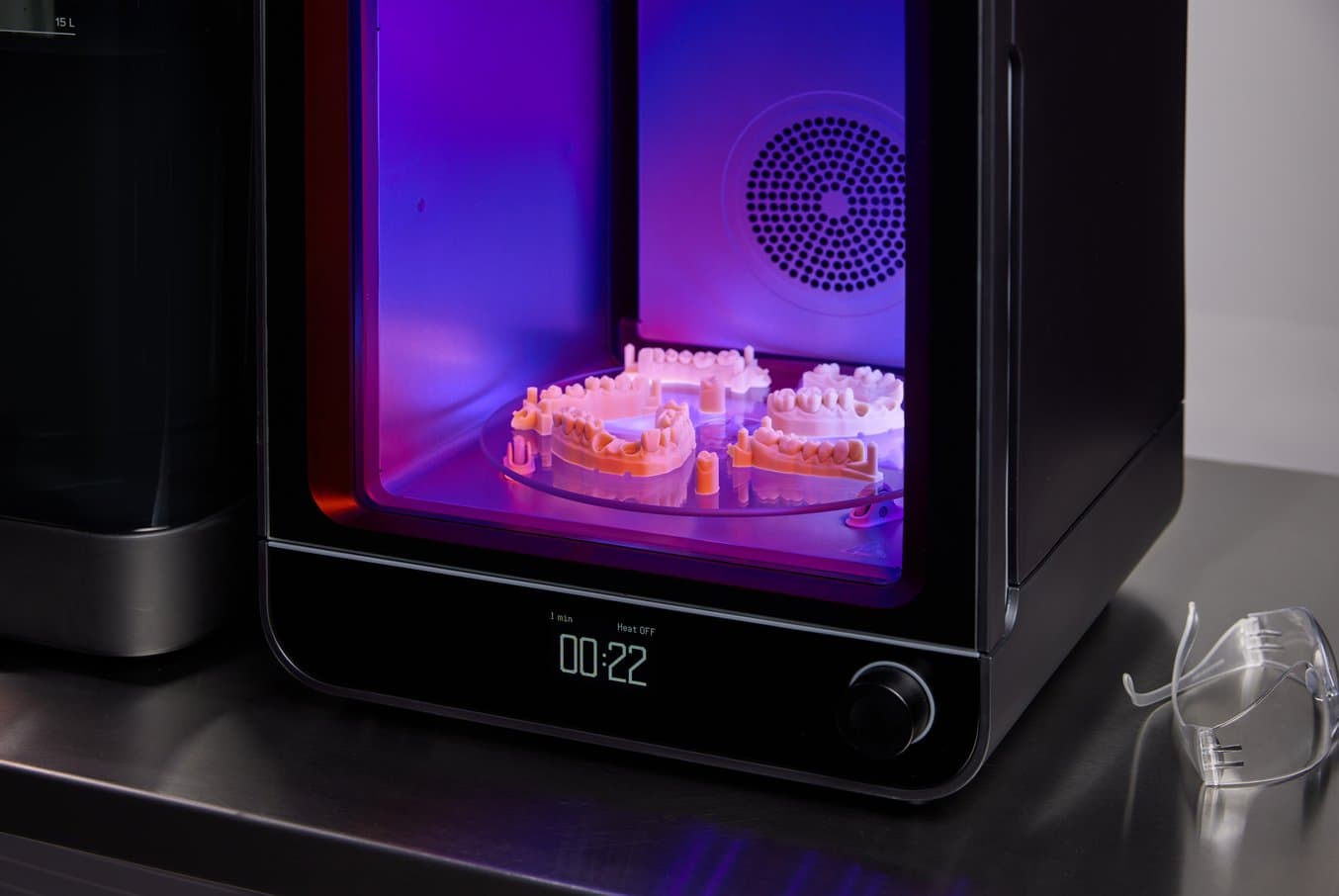 Close up on Form Cure (2nd Generation) with restorative dental models inside. The door is transparent purple as curing is in progress.